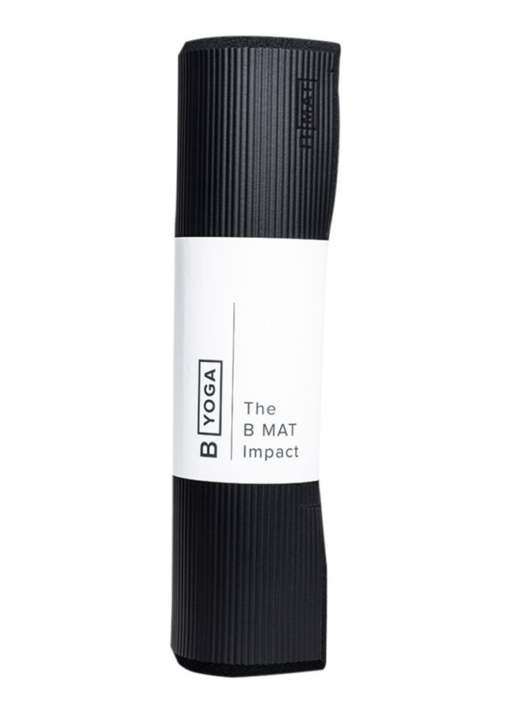 A rolled-up B Yoga mat with ribbed texture, predominantly black with a white label.